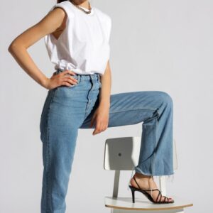 woman in white tank top and blue denim jeans sitting on white chair